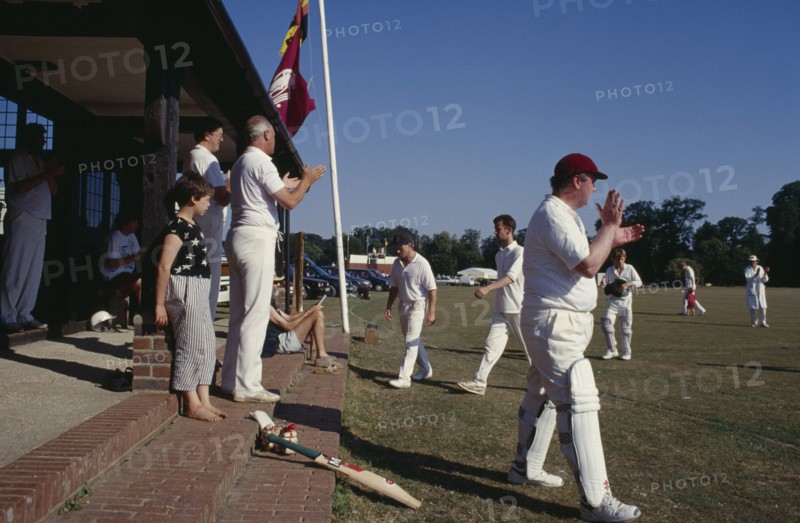 20027336 SPORT Ball Cricket Village cricket members applauding Team as they come off the pitch.