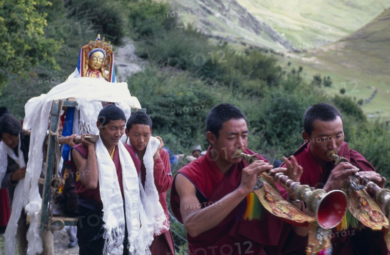 CHINA, Tibet, Lhasa, Drak Yerpa Monastery complex. New statue being carried up to the monastery by monks led by trumpet blowers.