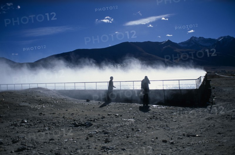 CHINA, Tibet, Lhasa, Yangpachen geothermal powerstation with two women stood beside a pool of steaming water.