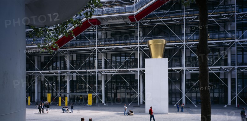 FRANCE, Ile de France, Paris, Pompidou Centre.  Exterior of building by Renzo Piano and Richard Rogers.  Sculpture and people in plaza area in front of entrance.