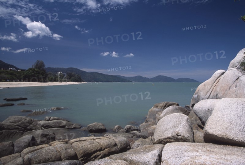 MALAYSIA, Penang, Batu Ferringhi, View over rocks and bay of turquoise water towards quiet sandy beach.