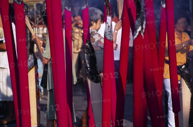 MALAYSIA, Penang, Georgetown, "Goddess of Mercy Temple, also known as Kuan Yin Teng.  Exterior with worshippers seen between large, pink, burning incense sticks."
