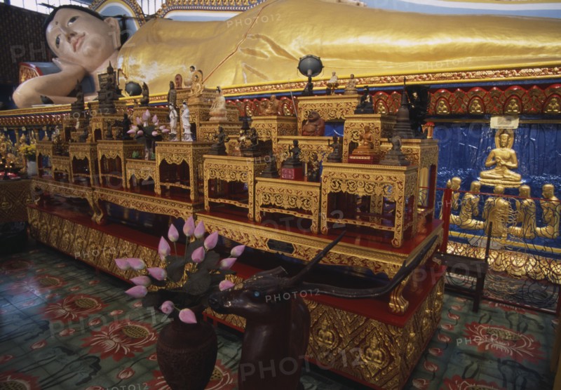MALAYSIA, Penang, Georgetown, Wat Chayamangkalaram.  Interior with thirty-two metre long reclining Buddha lying behind display of various smaller figures and statues.