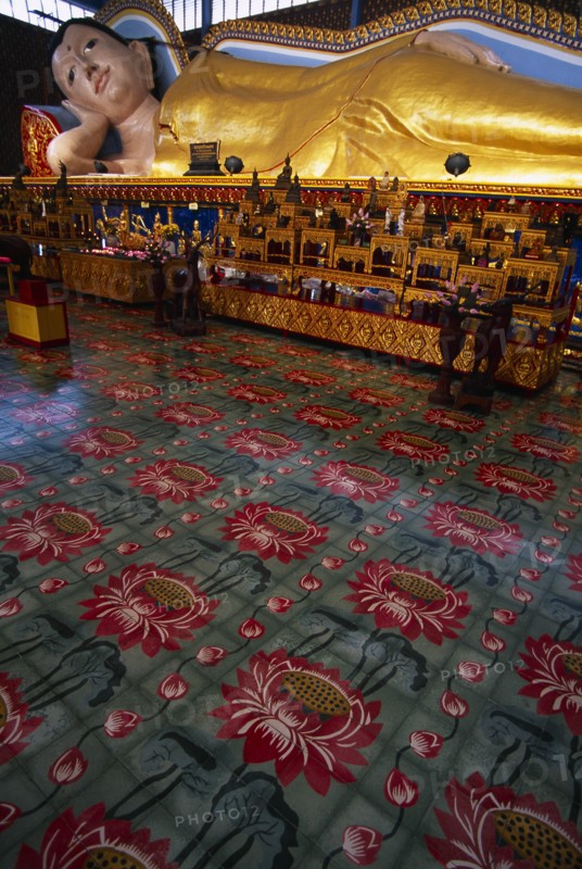 MALAYSIA, Penang, Georgetown, Wat Chayamangkalaram.  Interior with 32 metre long reclining Buddha lying behind display of various smaller figures and statues.