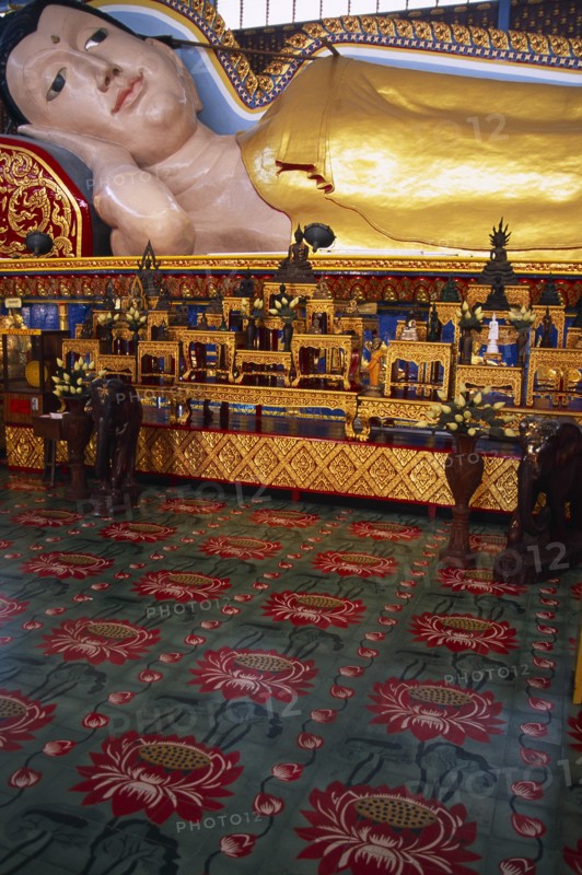 MALAYSIA, Penang, Georgetown, Wat Chayamangkalaram.  Interior with part view of 32 metre long reclining Buddha lying behind display of various smaller figures and statues.
