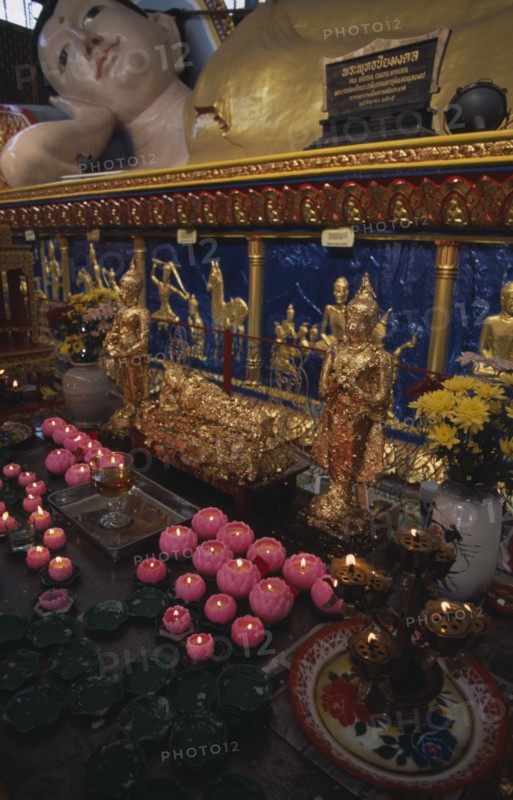 MALAYSIA, Penang, Georgetown, Wat Chayamangkalaram.  Interior.  Part view of  reclining Buddha lying behind smaller figures covered in gold leaf and lighted candles in the shape of lotus flowers.