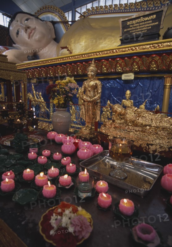 MALAYSIA, Penang, Georgetown, Wat Chayamangkalaram.  Interior.  Part view of  reclining Buddha lying behind smaller figures covered in gold leaf and lighted candles in the shape of lotus flowers.