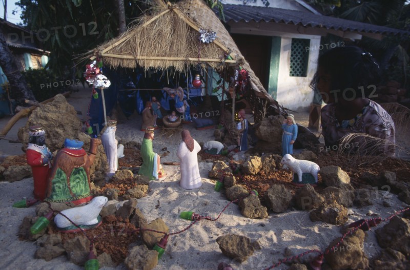 INDIA, Goa, Palolem, Young girl looking at Christmas nativity scene on sand.