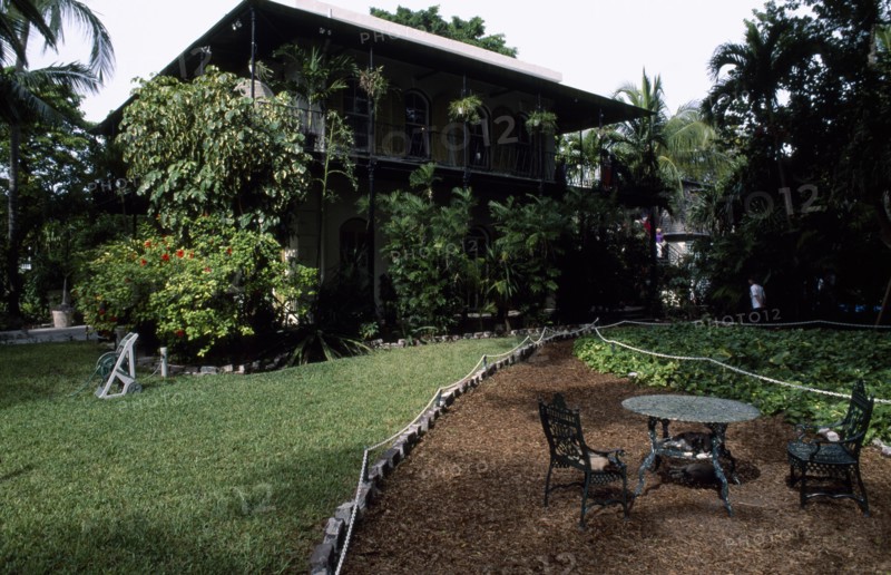 USA, Florida, Key West , "Hemmingway’s home, exterior and garden with iron table and cats asleep on chairs in the foreground"