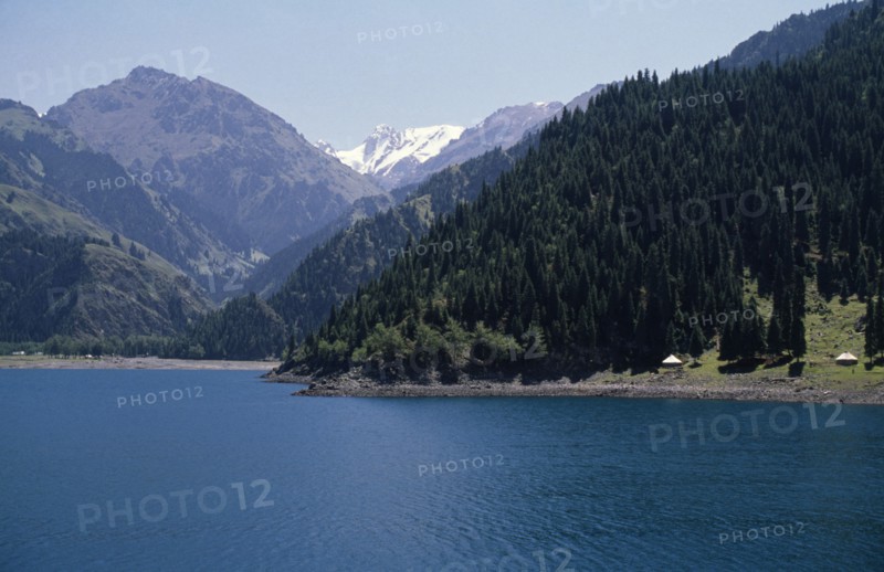 CHINA, Xinjiang, Heaven Lake, View over lake toward pine forests covering mountainous landscape