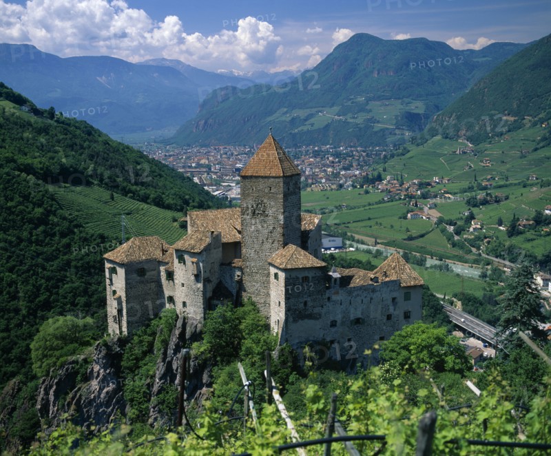 ITALY, Trentino Alto Adige, Bolzano, View over distant mountain village Karneid castle in foreground Summer time