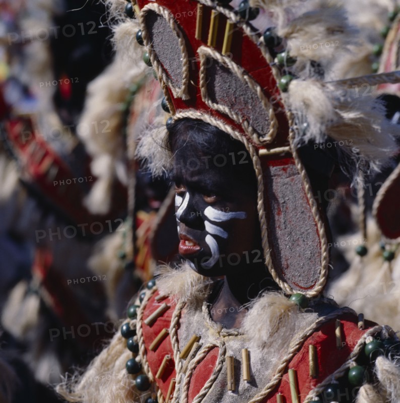 PHILIPPINES, Luzon, Manila, Young girl in costume at Ati-Atihan festival with a black painted face and wearing a headdress