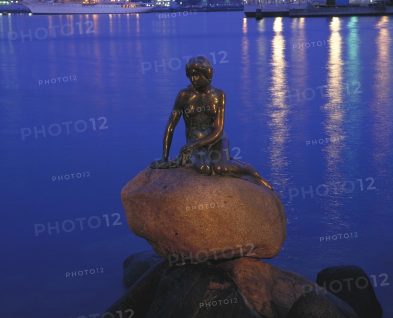 DENMARK, Zealand, Copenhagen, The Little Mermaid statue at night with lights reflected in the water