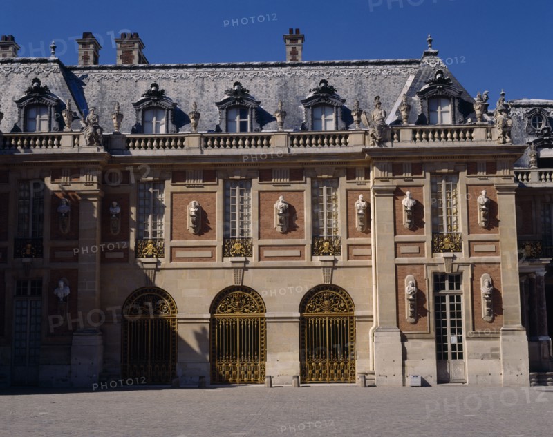 FRANCE, Ile de France, Yvelines, "Versailles. Part of palace with statues on walls, arches, balustraded roof and gravel in foreground"