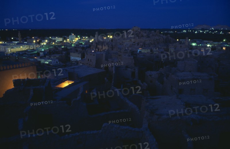 EGYPT, Western Desert, Siwa Oasis, View across town towards Shali Fortress at night with oasis in the background