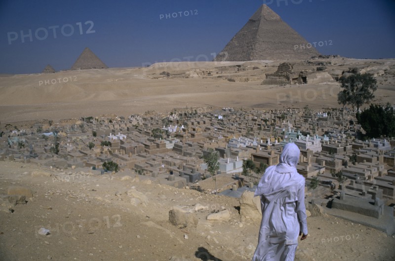 EGYPT, Cairo Area, Giza, The Pyramids with man standing in front of Muslim graveyard