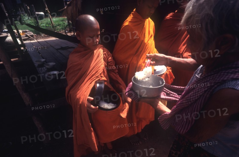 CAMBODIA, Religion, Young monks being served rice Alms.