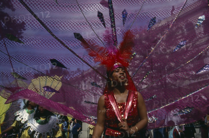 ENGLAND, London, "Notting Hill Carnival, dancer in pink and red costume following a float."