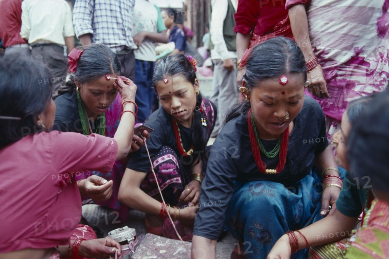 NEPAL, Religion, Young women receiving Tikas a mark of blessing on their forehead