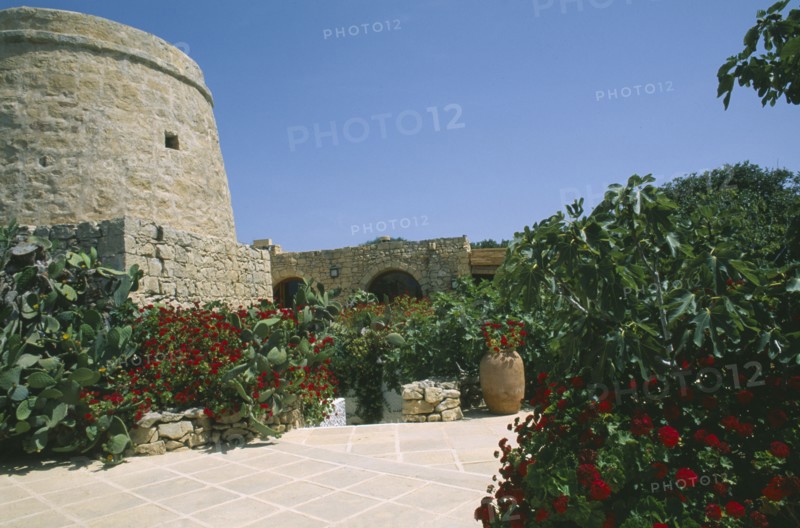 MALTA, Gozo, Ta’ Cenc, Entrance to Ta’ Cenc Hotel with traditional grain store and lined with flowers.