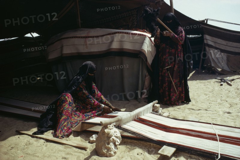 QATAR, Craft, Bedouin women weaving and spinning outside tent.