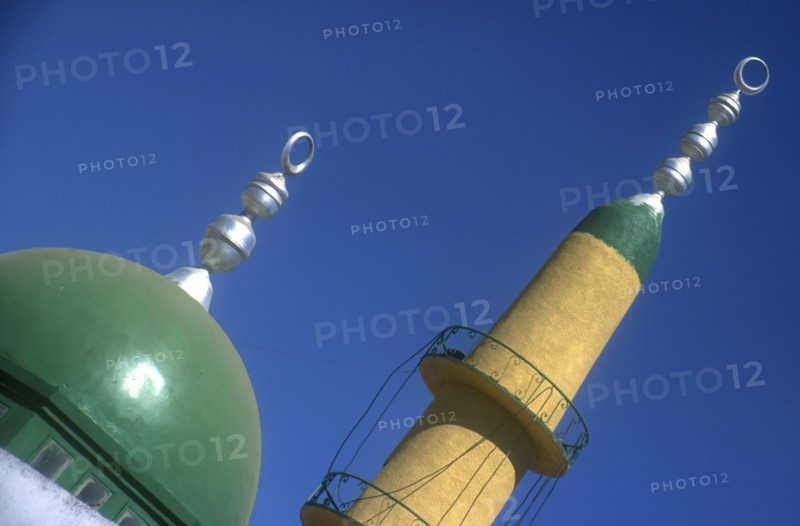 EGYPT, Nile Valley, Aswan, Elephantine Island. Minaret and dome of small mosque painted green and yellow against blue sky.