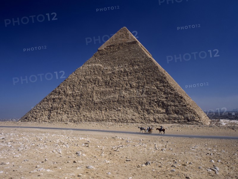 EGYPT, Cairo Area, Giza, Tourist horse and carriage passing by pyramid of Khufu.