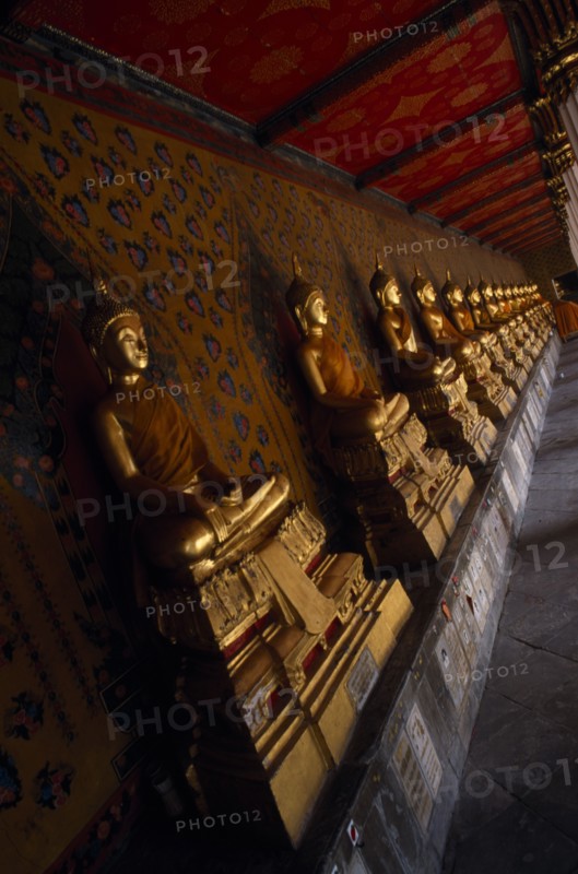 THAILAND, Bangkok Area, Bangkok, Wat Arun. Golden seated Buddha statues in cloister of Ordination Hall.