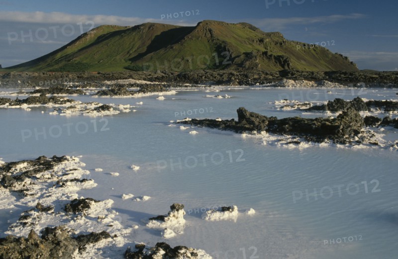 ICELAND, Gullbringu, Reykjanes Peninsula, Blue Lagoon at Svartsengi geo thermal power station.  Hot blue water with mineral deposits and mountain backdrop.