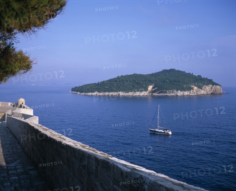 CROATIA, Dalmatia, Dubrovnik, Boat sailing between the City Walls or Gradske Zidine and Kolocep Island