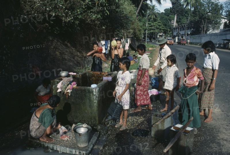 MYANMAR, Yangon, Washing at roadside tap.