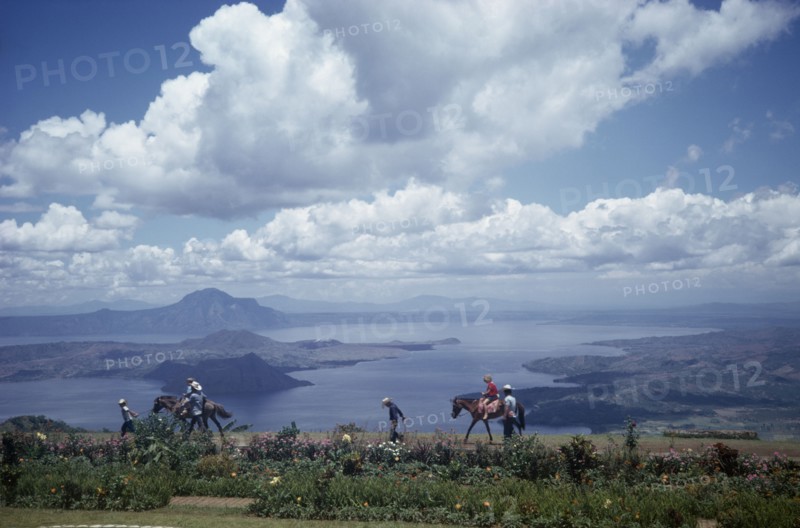 PHILIPPINES, Luzon Island, Taal Lake, Tourists being led on horses along shores of lake in volcanic crater.