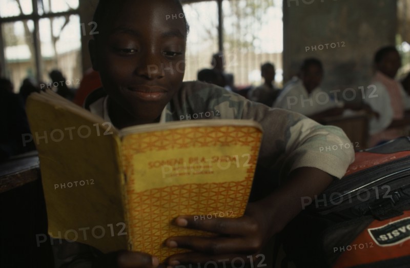 TANZANIA, Shinyanga, Mwenge Primary School child reading a text book in the classroom