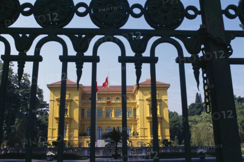 VIETNAM, North, Hanoi, The Presidential Palace yellow painted exterior facade seen through metal gate railings.