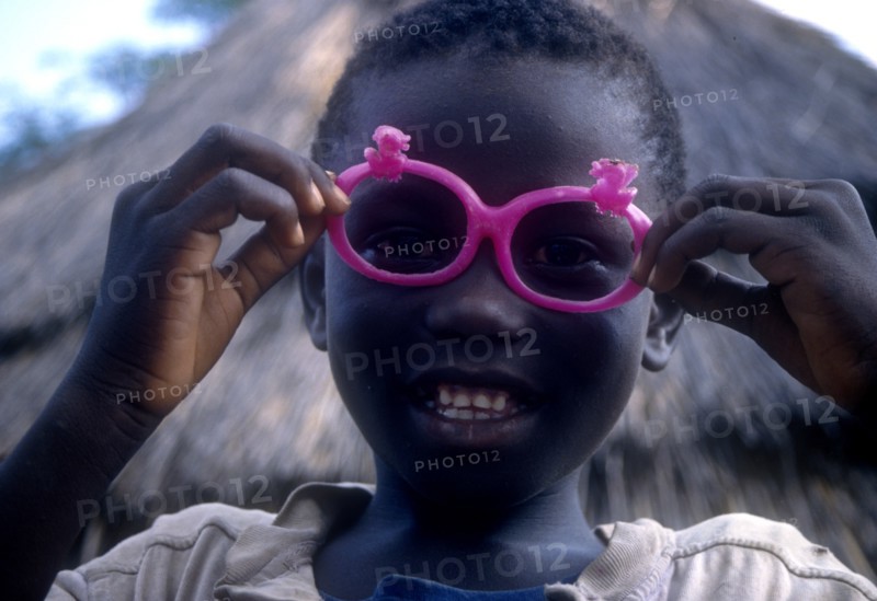 ETHIOPIA, Children, Portrait of a young Dimma Sudanese boy with pink sunglasses