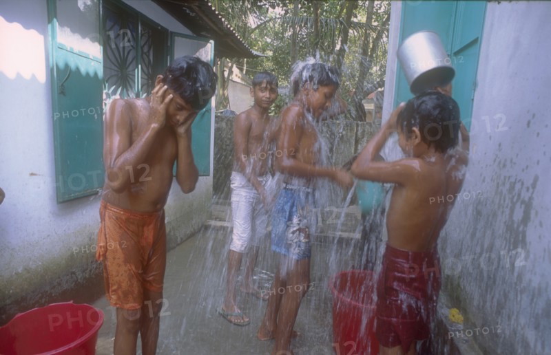 BANGLADESH, Savar, Dhaka, Street boys in a refuge home bathing using buckets and cups.