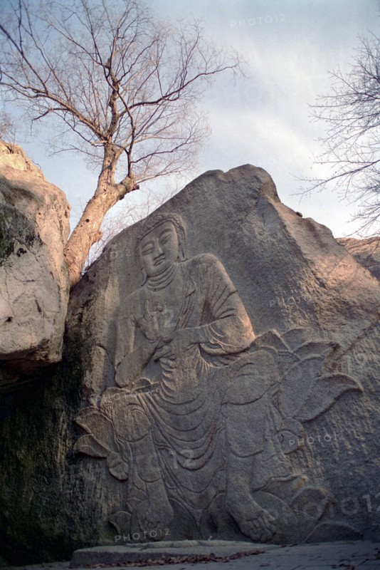 SOUTH KOREA, Songnisan National Park, Popchusa, Angled view of seated Buddha rock carving in cliff face