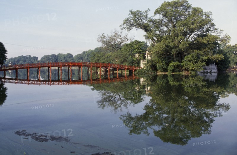 VIETNAM, North, Hanoi, The Huc or Rising Sun bridge and trees reflected in Hoan Kiem Lake.