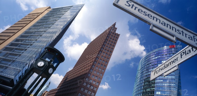 GERMANY, Berlin, Angled view of the city skyscrapers and clock with a sign post for Potsdamer Platz and Stresemannstrass in the foreground
