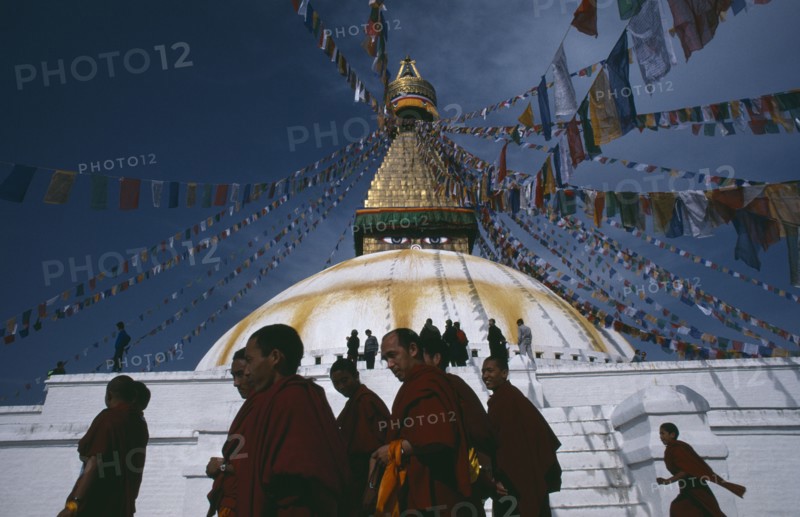 20049356 NEPAL  Kathmandu Tibetan families and monks of the Gelug pa sect walking around the Bodhanath stupa during New year festivities.  Lines of prayer flags overhead.