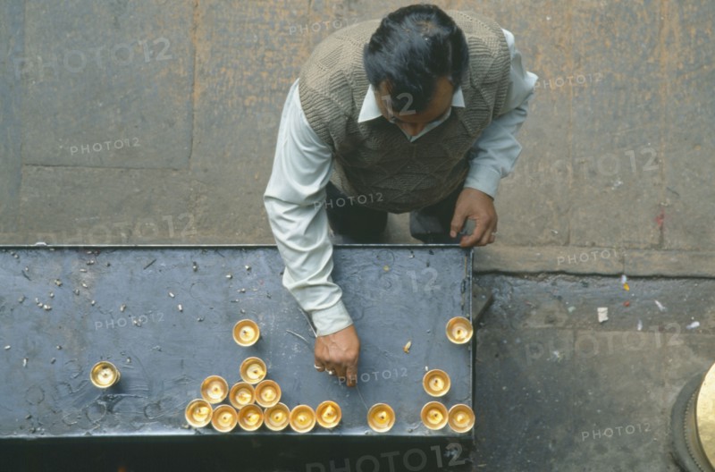 NEPAL, Patan, Looking down on man lighting butterwick candles at the Hiranyavarna Mahavihara Golden Temple