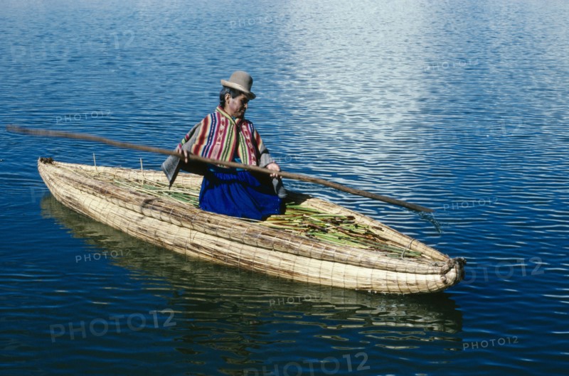PERU, Puno, Lake Titicaca, Uros woman on reed boat rowing to floating island.