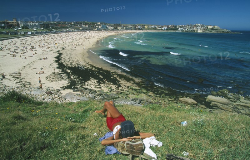 AUSTRALIA, New South Wales, Sydney, View over Bondi beach with woman sunbathing in the foreground