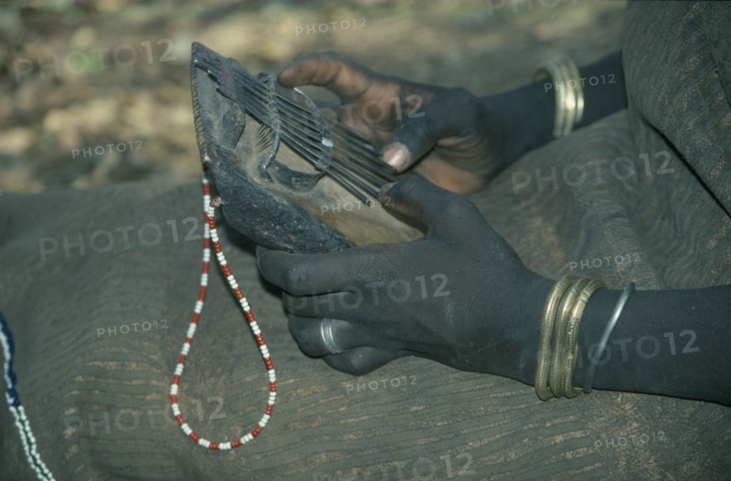 ETHIOPIA, Music, Cropped view of Mursi girl playing traditional thumb piano musical instrument.