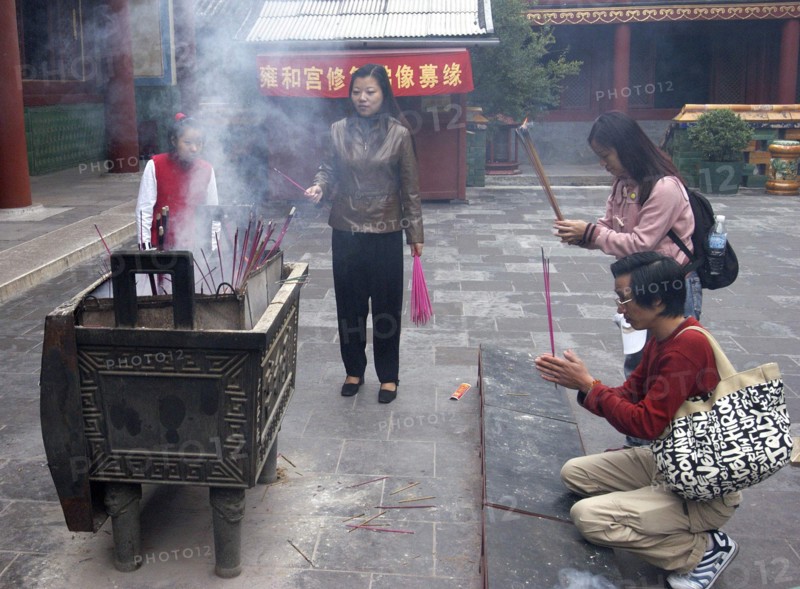 CHINA, Beijing, Lama Temple. People lighting incense during worship in the Temple courtyard