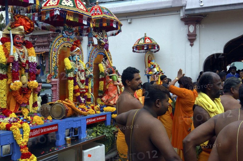 SINGAPORE, , Men and women standing beside a colourful shrine decorated with flower garlands at an Indian Temple