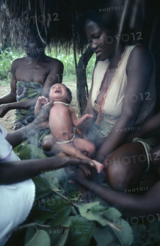 SUDAN, People, Azande women and child during ritual purification of new born baby in smoke.