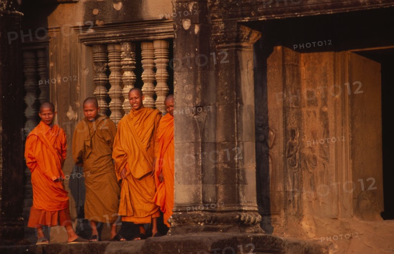 CAMBODIA, Siem Reap, Angkor Wat, Monks standing outside the west gallery at sunset