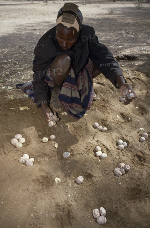 KENYA, North, People, Turkana man playing traditional mathematical game of Ajua.