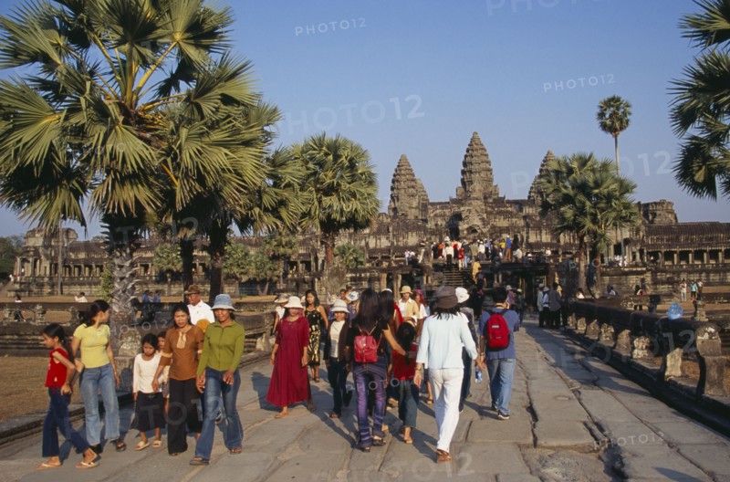 CAMBODIA, Siem Reap Province, Angkor Wat, Tourists on tree lined stone causeway leading to temple complex.  Many Cambodians visiting during Chinese New Year.
